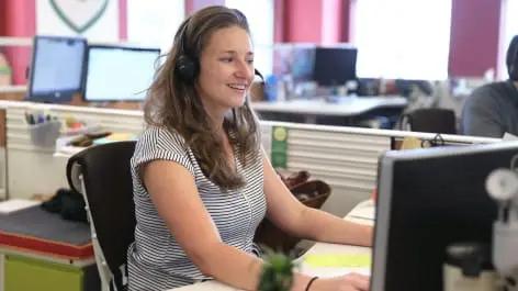 Woman with headset smiling while using computer