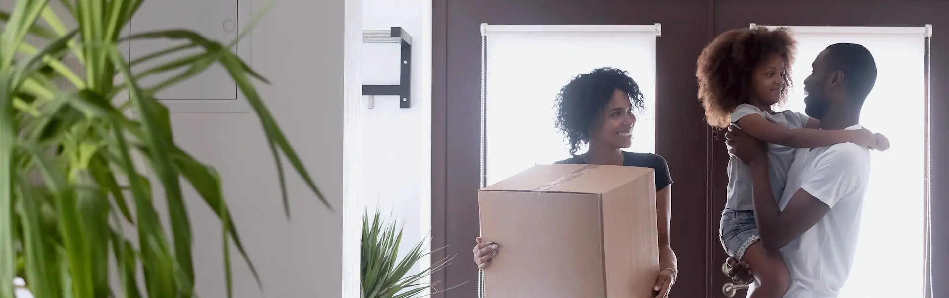 A man carrying a child and a woman are holding a cardboard box